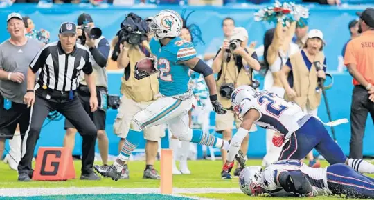  ?? AL DIAZ/MIAMI HERALD PHOTOS ?? Running back Kenyan Drake (32) scores to help the Dolphins defeat the Patriots on Sunday at Hard Rock Stadium in Miami Gardens, Fla. The Dolphins won 34-33.