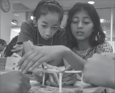  ??  ?? ABOVE: Mia Kaplan, left, and Jhalak Singh work to create a plastic straw structure during a 3D printing session at a recent FOCUS camp at George Mason University in Fairfax, Virginia. The camp is designed to expose middle school-aged females of color...
