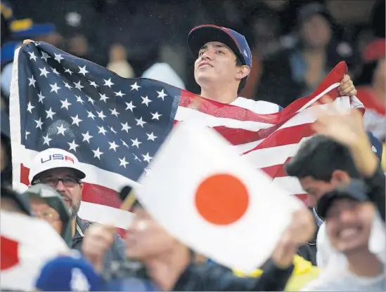  ?? Photograph­s by Allen J. Schaben Los Angeles Times ?? A FAN holds a U.S. f lag that dwarfs Japanese f lags in the Dodger Stadium stands during a World Baseball Classic game between the countries.