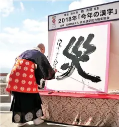  ??  ?? Seihan Mori uses an ink-soaked calligraph­y brush to write the Chinese character of‘disaster’ at the temple in Kyoto. — AFP photo