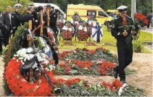  ?? Olga Maltseva / AFP / Getty Images ?? A navy officer places flowers at the grave in St. Petersburg of one of 14 seamen killed in a fire on a research submersibl­e.