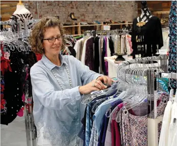  ?? Janelle Jessen/Herald-Leader ?? Kristen Stewart, director of Siloam Springs Beautiful Lives, sorts through some of the clothing the store has on the rack.