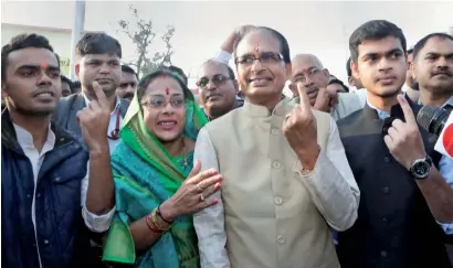  ?? — PTI ?? Madhya Pradesh Chief Minister Shivraj Singh Chouhan, his wife Sadhna Singh and two sons Kartikeya and Kunal, show their marked fingers after casting their votes for assembly elections at Jait village in Bhopal on Wednesday.