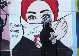  ?? HADI MIZBAN — THE ASSOCIATED PRESS ?? A woman stands in front of graffiti at the Saadoun Tunnel, in Baghdad, Iraq.