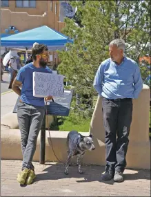  ??  ?? Jordan Gyovai holds a sign reading ‘Viruses are not contagious’ as he speaks to members of the public at the Taos Farmers Market on Saturday (May 15).