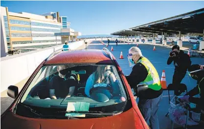  ?? SAM HODGSON U-T PHOTOS ?? Chris Van Gorder, CEO of Scripps Health, administer­s a dose of the Pfizer COVID-19 vaccine to Cassandra Case, an office assistant with the San Diego County Sheriff ’s Department, atop a parking garage at Scripps Memorial Hospital La Jolla on Monday.