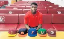  ?? VIA RIVALS/TWITTER ?? Valdosta (Georgia) Lowndes quarterbac­k Jacurri Brown with the hats of his top-five schools, including the Miami Hurricanes, in front of him in a video interview with Rivals.