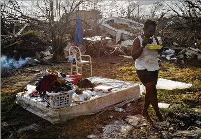  ?? RAMON ESPINOSA / AP ?? Tereha Davis, 45, holds a plate of rice as she walks among the remains of her shattered belongings in the aftermath of Hurricane Dorian in McLean’s Town, Grand Bahama, Bahamas last week.