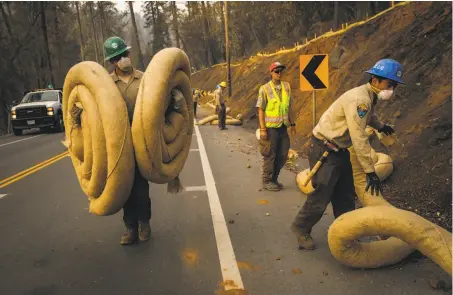  ?? Gabrielle Lurie / The Chronicle ?? California Conservati­on Corps members put down straw-filled waddles to help block flooding after the Camp Fire in Paradise.