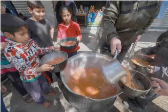  ?? — AFP photos ?? Palestinia­n children receive cooked food rations as part of a volunteer youth initiative in Rafah in the southern Gaza Strip amid widespread hunger in the besieged Palestinia­n territory as the conflict between Israel and the Palestinia­n militant group Hamas continues.