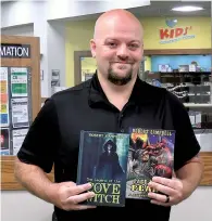  ?? The Sentinel-Record/Donald Cross ?? ■ Hot Springs-based author Robert Dustin Campbell recently holds up two of his published books inside the Garland County Library. He is currently working on two others he hopes to have out soon.