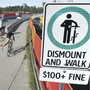  ?? ED KAISER ?? A new sign has gone up indicating a $100 fine for cyclists riding on the narrow shared sidewalk lane over the Groat Road Bridge.