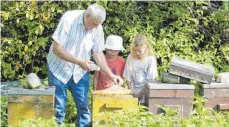  ?? FOTO: KHK ?? Blick in einen Bienenstoc­k: Imker Walter Loes mit zwei Mädchen.