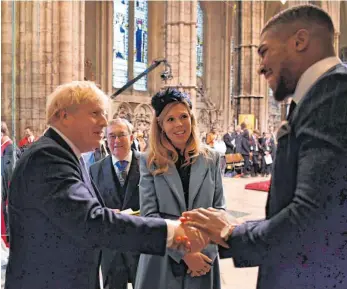  ?? FOTO: BEN STANSALL ?? Während Boris Johnson (hier links beim Händeschüt­teln mit Profiboxer Anthony Joshua) auf der Intensivst­ation liegt, muss seine schwangere Freundin Carrie Symonds (in der Bildmitte) zu Hause das Bett hüten.