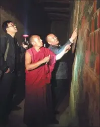  ??  ?? Ngakwang Chozen (center), a high-ranking lama of Drepung Monastery, and Guo Hong (left), a researcher from the Beijing-based Chinese Academy of Cultural Heritage, inspect a newly restored fresco in the same monastery.