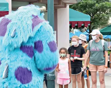  ?? Joe Burbank/Orlando Sentinel/TNS ?? Guests wave to Sulley of “Monsters, Inc.” during a pop-up appearance of Pixar characters at Disney’s Hollywood Studios on July 16 at Walt Disney World in Orlando, on the second day of the park’s re-opening.
