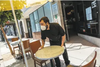  ?? Nick Otto / Special to The Chronicle ?? Dylan Boon wipes off tables placed on the sidewalk where patrons can sit at Il Cilentano in North Beach — when Phase 2B of the reopening that will allow outdoor dining begins June 15.