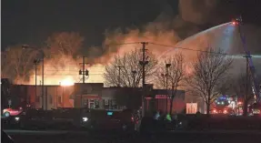  ?? ROBIN BUCKSON/AP ?? Fire department­s battle an industrial fire near 15 Mile Road and Groesbeck Highway in the Detroit suburb of Clinton Township on Monday.