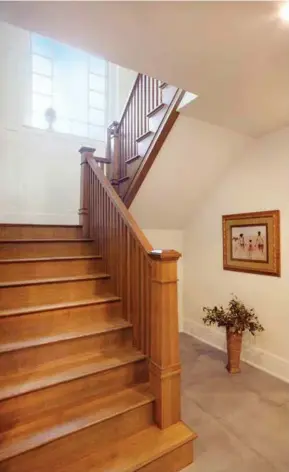  ??  ?? Quarter-sawn white oak defines this Mission style staircase with built-in wine drawers beneath and ascending wainscotin­g. A large-scale, opaque glass window provides soft sunlight.