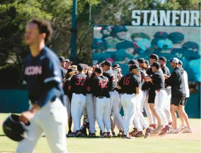  ?? D. ROSS CAMERON/AP ?? A Uconn player walks off the field while Stanford players celebrate after the Cardinal closed out a 10-5 victory in Game 3 to win the Super Regional in Palo Alto, California.