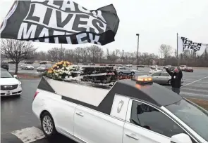  ?? JOSHUA A. BICKEL/COLUMBUS DISPATCH ?? Mourners wave Black Lives Matter flags as the hearse carrying Andre Hill leaves the First Church of God following his funeral on Jan. 5 at First Church of God in Columbus