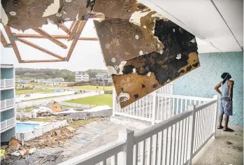  ?? TRAVIS LONG/THE NEWS & OBSERVER ?? Marshall Brewer looks for damage outside his apartment Friday in Nags Head, North Carolina, after Hurricane Dorian tore the roof off of a neighborin­g building spreading a swath of debris.