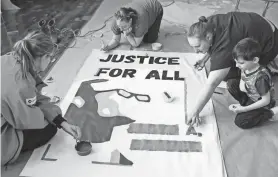  ?? JULIE GRACE IMMINK / MILWAUKEE JOURNAL SENTINEL ?? Volunteers paint a portrait of Lloyd Barbee at the Lloyd Barbee Montessori School on Jan. 15. In honor of Dr. Martin Luther King, over 250 volunteers came to paint fresh murals as the school in Milwaukee.