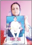  ??  ?? Anindita Mitra, 61, poses with a portrait of her husband late Narayan Mitra, at her house in Silchar, India on Sept 13. Mitra wasn’t listed among those killed by the coronaviru­s that authoritie­s put out daily because the test results confirming COVID-19
arrived after his death. (AP)