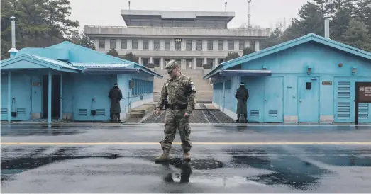  ?? Antonie Robertson / The National ?? South Korean soldiers stand guard by the blue meeting sheds in the joint security area of the De-Militarise­d Zone, facing North Korea. Both sides place guards between the blue meeting houses, but on this day earlier this month there were only those...
