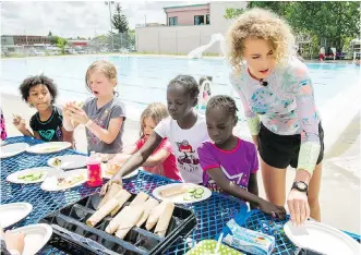  ?? LYLE ASPINALL ?? Calgary Swims for Lunch Foundation co-founder Makena Hind helps kids during a free program at the Forest Lawn pool on Wednesday. The hour-long program runs three days a week.