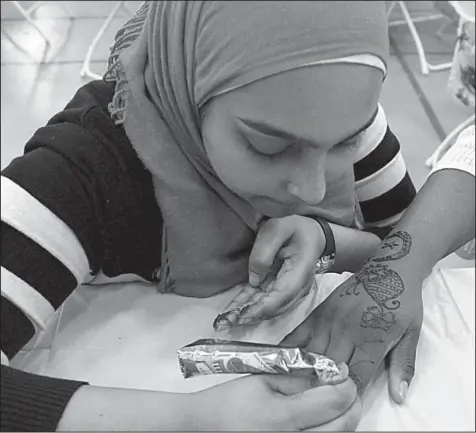  ?? Arkansas Democrat-Gazette/FRANCISCA JONES ?? Mariam Khan (left) applies henna to the hand of Janecia Collins at the Little Rock Internatio­nal Food Festival on April 15. Khan has been working with henna, the temporary body dye prepared from the plant of the same name, for about 10 years.