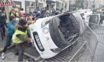  ?? — AFP ?? Demonstrat­ors destroy cars during a protest of ‘yellow vests’ against rising oil prices and living costs, near the Champs Elysees in Paris, on Saturday.