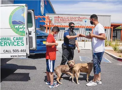  ?? ROBERTO E. ROSALES/JOURNAL ?? At Bernalillo County’s Animal Care and Resource Center shelter, officer Gerardo Acevedo, center, returns two dogs to their owner, Sergio Sisneros, and his son, Emiliano Sisneros, 10, after the animals got loose from their house. The county will use $500,000 in bond sale proceeds to fund a study on space needs and design work at the 2-year-old shelter.