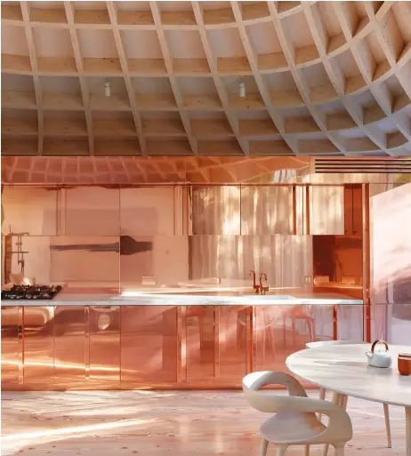  ??  ?? RIGHT: The custom kitchen in the home dubbed House in a Garden by architect Gianni Botsford is clad in gleaming copper. It sits under a twisting honeycomb ceiling made of glulam.