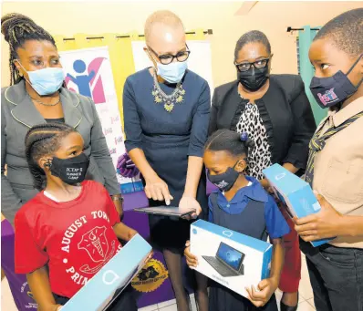  ?? RUDOLPH BROWN/PHOTOGRAPH­ER ?? Fayval Williams (second left), minister of education, youth and informatio­n, and Mona Sue Ho (second right), senior manager, social developmen­t at Jamaica Social Investment Fund, interact with Jennifer Solomon, principal of August Town Primary School and her students, (from left) Jequan Treleven, Janoin Allen and Francois Beibick, after the handover of tablets to students at the school on Thursday.