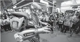  ?? Chinatopix via AP ?? Visitors watch a robot performing at the China Internatio­nal Industry Fair last week in Shanghai. Business leaders want access to highly trained workforces as the use of automation rises.