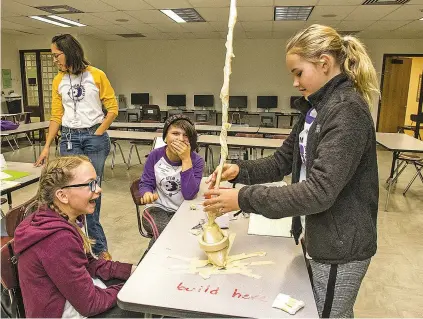  ?? JANE PHILLIPS/FOR THE NEW MEXICAN ?? Chloe Gessler, 10, from left, Keyana LeRouge Peña, 10, and Hazel Hits, 11, make a tower during Reach for the Sky: An Engineerin­g Challenge during the annual Expanding Your Horizons Santa Fe Conference on Saturday at Santa Fe Community College. Hope Catill, background, works with other students.