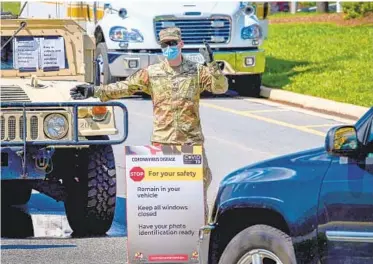  ?? JERRY JACKSON/BALTIMORE SUN ?? A Maryland National Guardsman directs traffic coming in for coronaviru­s testing at the Glen Burnie VEIP station.