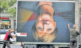  ?? REUTERS ?? (Left) Workers remove an election campaign billboard showing German Chancellor Angela Merkel’s face, which has been vandalised with a Hitleresqu­e moustache; (right) AfD coleader Frauke Petry storms out after quitting the party.