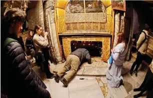  ?? AFP ?? A Christian worshipper kisses a silver star at the Grotto, believed to be the exact spot where Jesus Christ was born, as others pray at the Church of the Nativity in Bethlehem. —