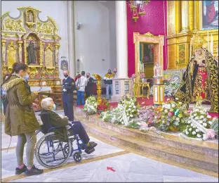  ??  ?? Catholic worshipers pay respects to a figure of Virgin Mary inside El Cerro church in Seville.