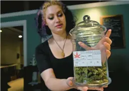  ?? KIM HAIRSTON/BALTIMORE SUN ?? Mana Colter, retail specialist at Charm City Hemp, holds a jar with THCA-infused buds.