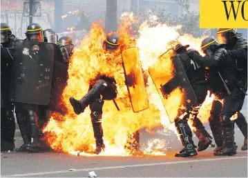  ?? ZAKARIA ABDELKAFI/AFP/GETTY IMAGES ?? French anti-riot police officers are engulfed in flames as they face protesters during a march for the annual May Day workers’ rally in Paris Monday. The traditiona­l rallies gained extra resonance ahead of Sunday’s runoff vote.
