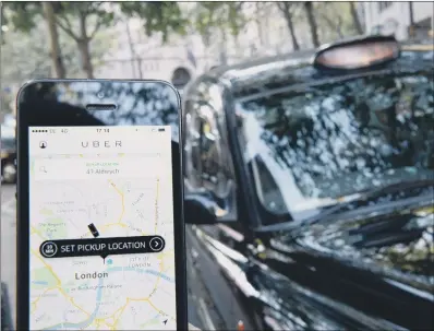  ??  ?? CABBIE ANGER: A smartphone displaying the Uber app as taxis line up on Fleet Street during a protest in London.