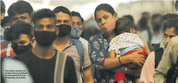  ??  ?? Una mujer camina con su hijo entre la multitud, en una estación de tren de Bombay, en la India.