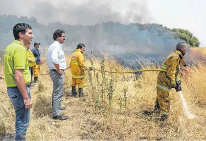  ??  ?? El funcionari­o provincial -de camisa- recorrió la zona del incendio y destacó la tarea que llevan adelante los bomberos .