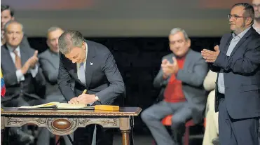  ?? ARCHIVO ?? Juan Manuel Santos firma el acuerdo final en el teatro Colón, ante la mirada de Rodrigo Londoño.