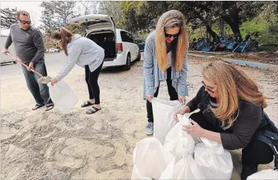  ?? AL SEIB TNS ?? Candra Emmeluth, right, receives help from family as she fills sand bags in Montecito, California.
