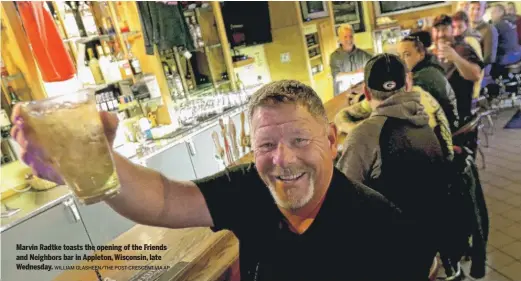  ?? WILLIAM GLASHEEN/THE POST-CRESCENT VIA AP ?? Marvin Radtke toasts the opening of the Friends and Neighbors bar in Appleton, Wisconsin, late Wednesday.