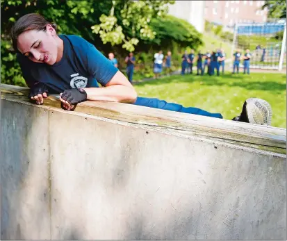  ?? SEAN D. ELLIOT/THE DAY ?? U.S. Coast Guard Academy Class of 2022 swab Sophia Furigay heaves herself over the wall on the obstacle course Friday as swabs face their Sea Trials, a series of physical, team-building challenges that marks the end of their seven-week Swab Summer indoctrina­tion. The Zulu One and Zulu Two companies of swabs will embark on the Coast Guard training barque Eagle this weekend.